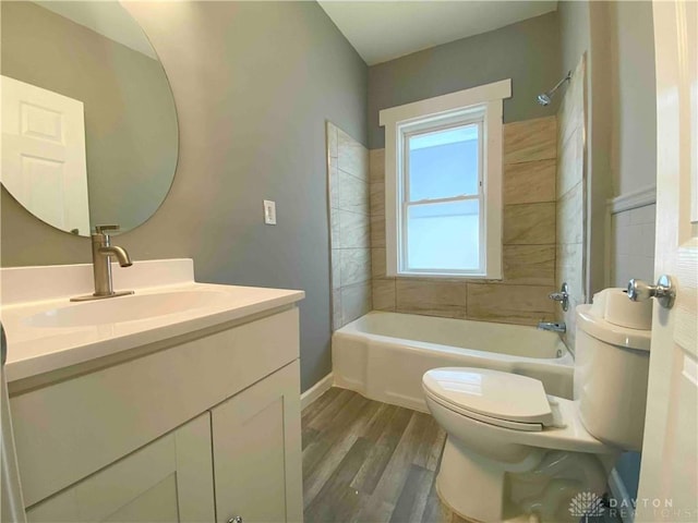 full bathroom featuring vanity, tiled shower / bath, hardwood / wood-style flooring, and toilet