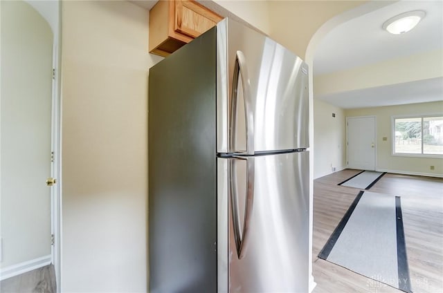 kitchen with stainless steel fridge, light brown cabinets, and light wood-type flooring