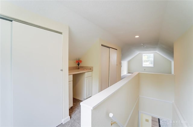 hallway featuring light carpet and vaulted ceiling