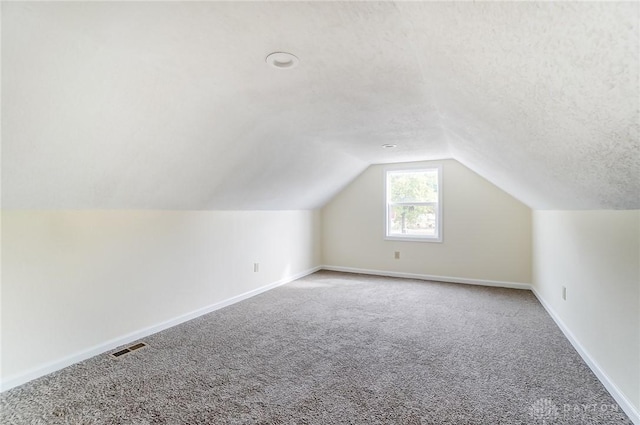 bonus room featuring carpet, lofted ceiling, and a textured ceiling