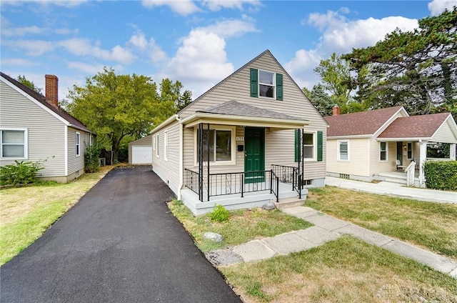 bungalow featuring an outbuilding, a porch, a garage, and a front lawn