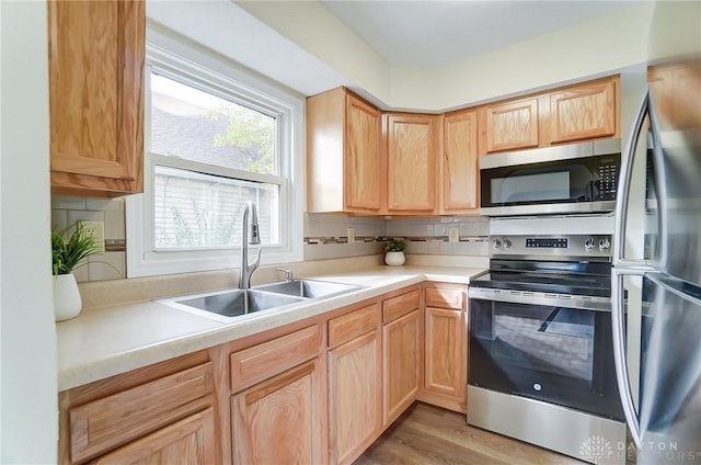 kitchen featuring appliances with stainless steel finishes, sink, backsplash, light hardwood / wood-style floors, and light brown cabinets