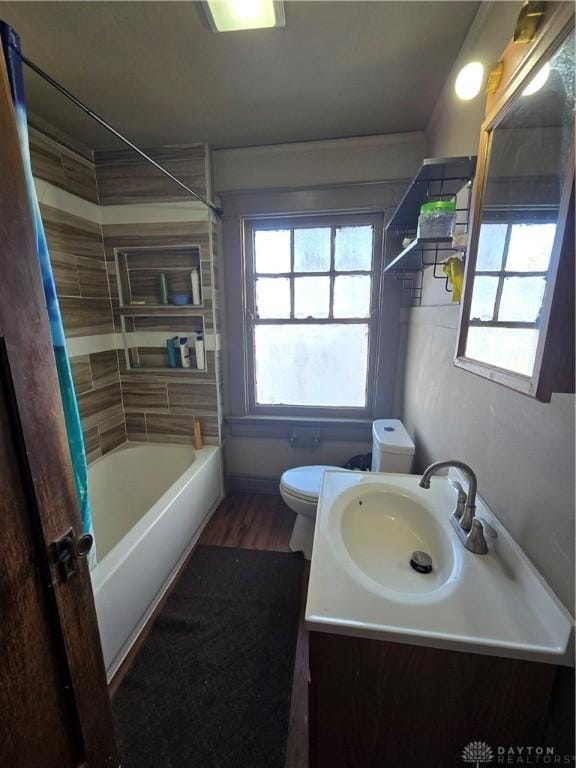 full bathroom featuring vanity, wood-type flooring, a wealth of natural light, and toilet