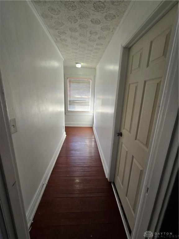 corridor featuring crown molding and dark hardwood / wood-style flooring