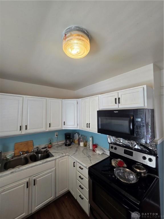 kitchen with sink, white cabinetry, electric range oven, dark hardwood / wood-style floors, and light stone countertops