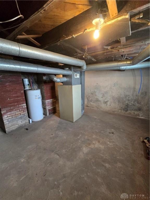 basement featuring water heater and brick wall