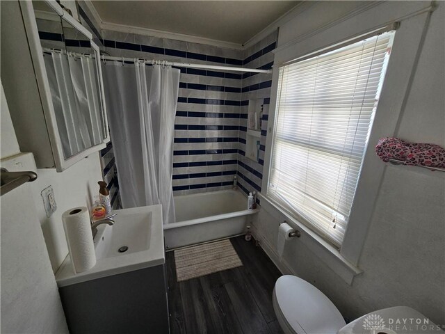 full bathroom featuring hardwood / wood-style flooring, shower / bathtub combination with curtain, ornamental molding, and toilet