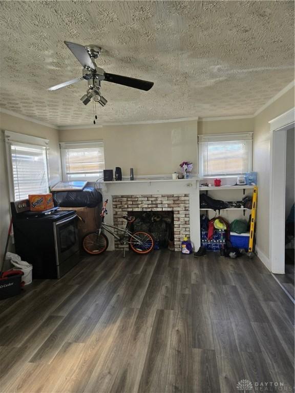 living room featuring ceiling fan, a brick fireplace, dark wood-type flooring, and a textured ceiling