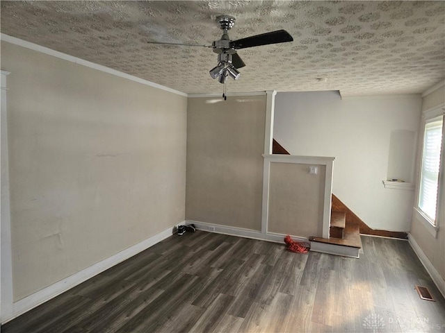 empty room featuring ceiling fan, dark wood-type flooring, ornamental molding, and a textured ceiling