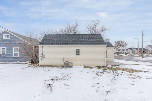 snow covered back of property featuring central AC unit