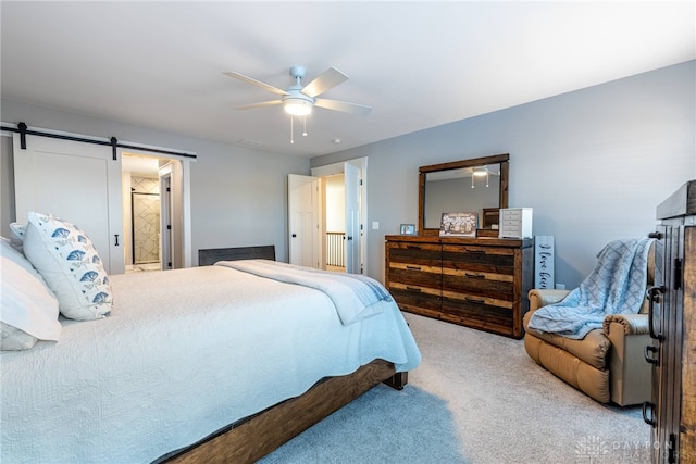 carpeted bedroom with a barn door and ceiling fan