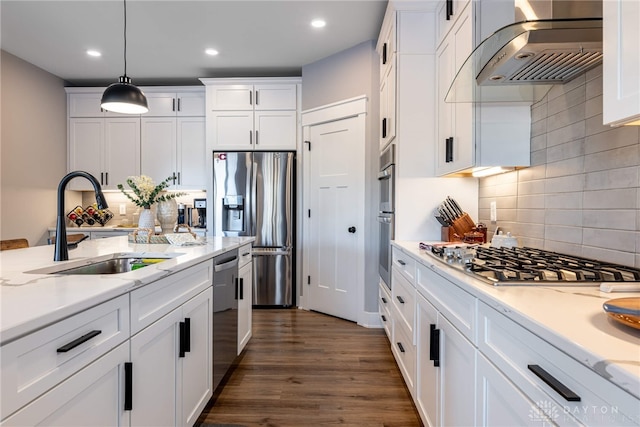 kitchen featuring sink, appliances with stainless steel finishes, hanging light fixtures, white cabinets, and wall chimney exhaust hood