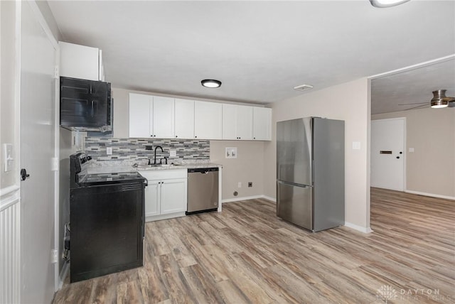 kitchen with sink, white cabinetry, backsplash, black appliances, and light wood-type flooring