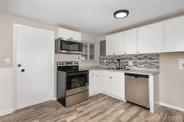 kitchen featuring appliances with stainless steel finishes, light hardwood / wood-style floors, sink, and white cabinets