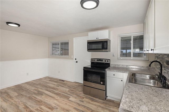 kitchen featuring light wood-type flooring, appliances with stainless steel finishes, sink, and white cabinets