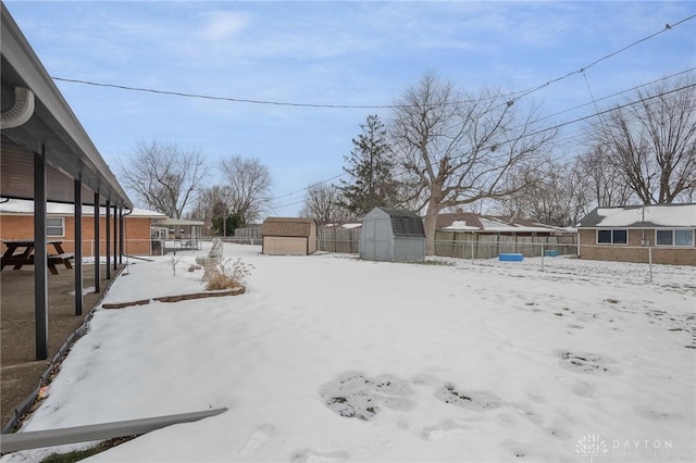 yard layered in snow with a storage shed