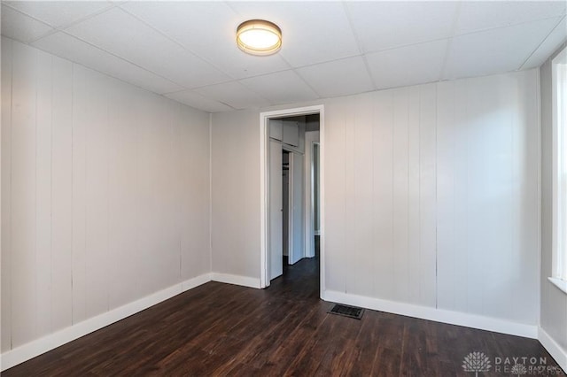 spare room featuring dark wood-type flooring and a paneled ceiling