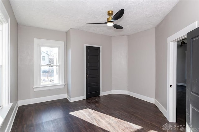 unfurnished room featuring dark hardwood / wood-style flooring, ceiling fan, and a textured ceiling