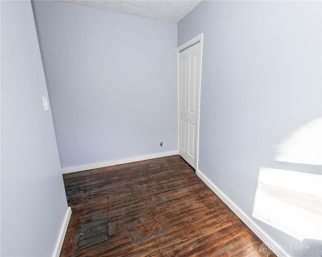 spare room with dark hardwood / wood-style floors and a textured ceiling