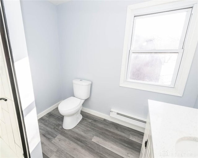 bathroom with a baseboard radiator, toilet, baseboards, wood finished floors, and vanity