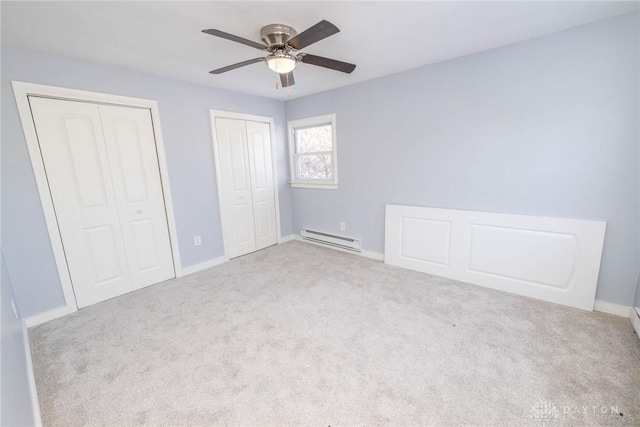 unfurnished bedroom featuring multiple closets, ceiling fan, carpet floors, and a baseboard heating unit