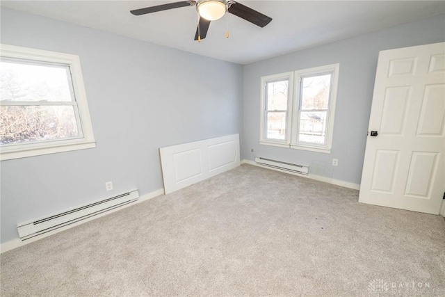 spare room with plenty of natural light, a baseboard heating unit, and light colored carpet