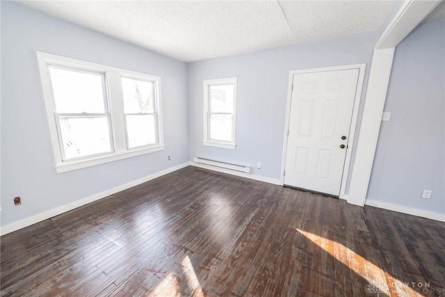 unfurnished room with a baseboard heating unit, dark wood-type flooring, and a textured ceiling