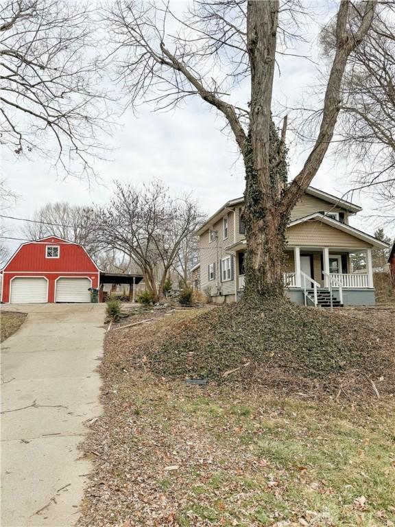 view of side of property with a porch, a garage, and an outdoor structure