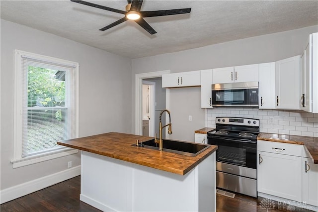 kitchen featuring butcher block counters, sink, white cabinetry, an island with sink, and stainless steel appliances