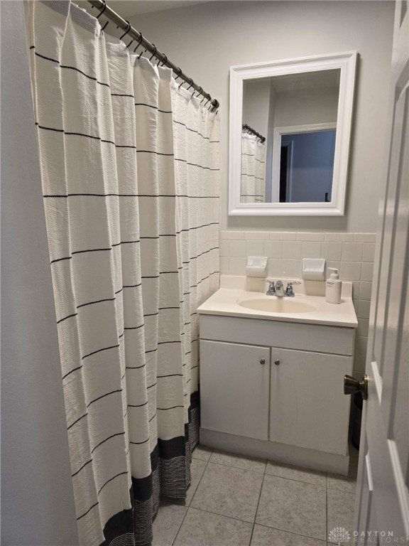 full bathroom featuring wainscoting, vanity, tile walls, and tile patterned floors