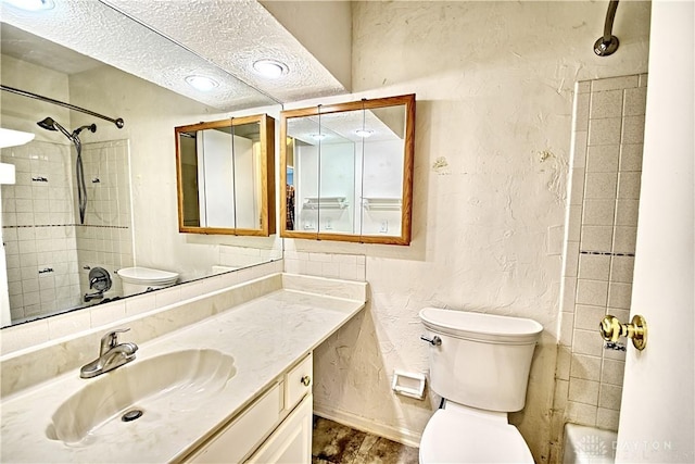 full bathroom with tiled shower / bath combo, vanity, a textured ceiling, and toilet