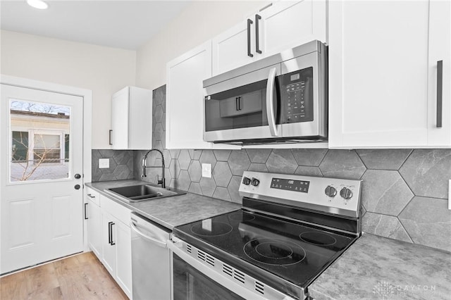 kitchen with sink, white cabinetry, appliances with stainless steel finishes, light hardwood / wood-style floors, and decorative backsplash