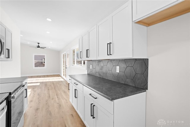 kitchen with light hardwood / wood-style flooring, white cabinetry, tasteful backsplash, stainless steel electric range oven, and vaulted ceiling