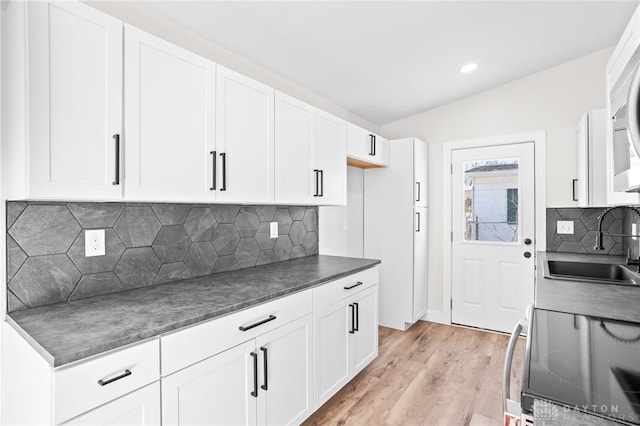 kitchen featuring white cabinetry, sink, light hardwood / wood-style floors, and decorative backsplash