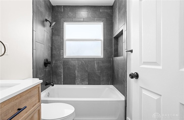 full bathroom featuring vanity, tiled shower / bath combo, and toilet