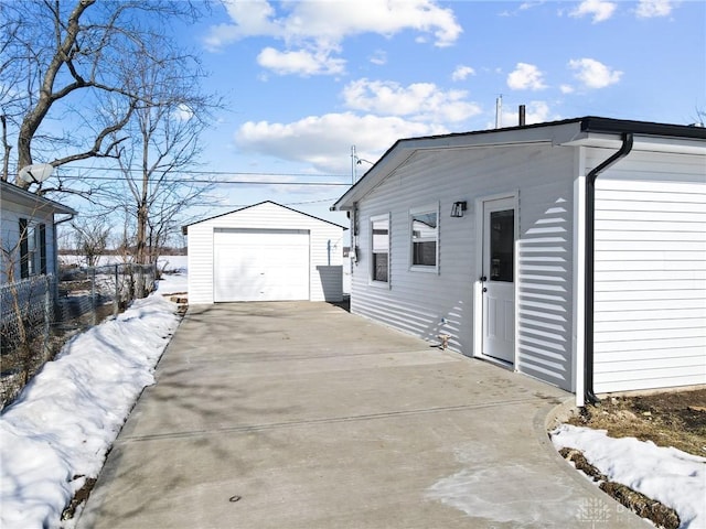 snow covered property featuring a garage and an outdoor structure