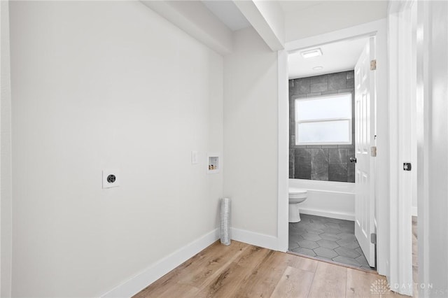 bathroom with tiled shower / bath, hardwood / wood-style floors, and toilet