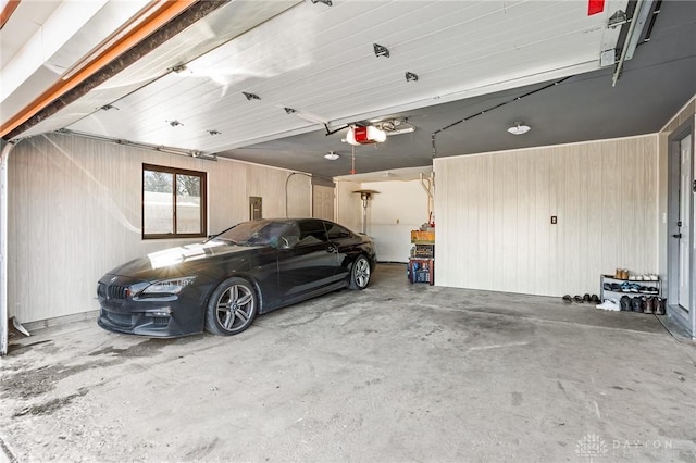 garage featuring a garage door opener and wood walls