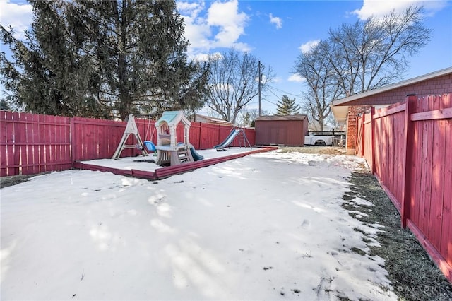 yard layered in snow with a playground and a shed