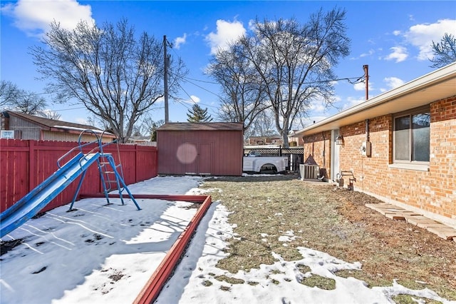 snowy yard featuring central air condition unit and a storage unit