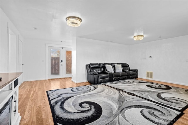 living room with french doors and light wood-type flooring