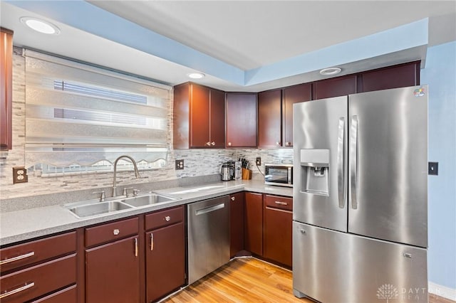 kitchen with sink, backsplash, light hardwood / wood-style floors, and appliances with stainless steel finishes