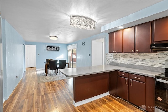 kitchen featuring electric range oven, tasteful backsplash, extractor fan, light hardwood / wood-style floors, and kitchen peninsula