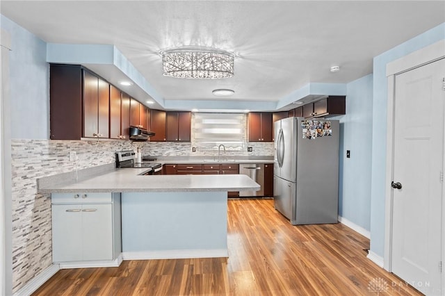 kitchen with stainless steel appliances, kitchen peninsula, sink, and backsplash