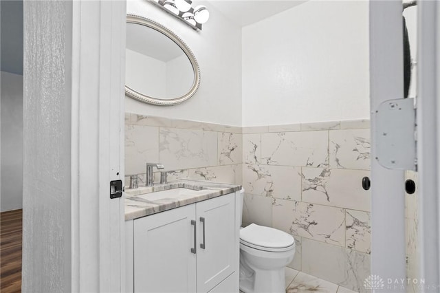 bathroom featuring tile walls, vanity, and toilet