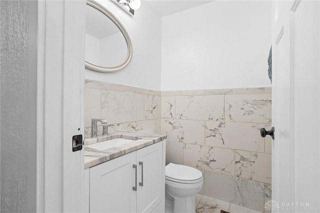 bathroom featuring tile walls, vanity, and toilet