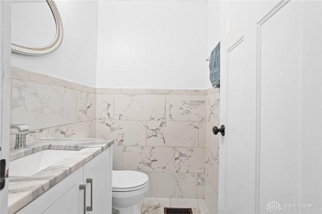 bathroom with vanity, tile walls, and toilet