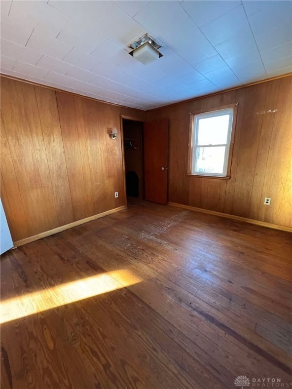 unfurnished room featuring dark wood-type flooring and wood walls