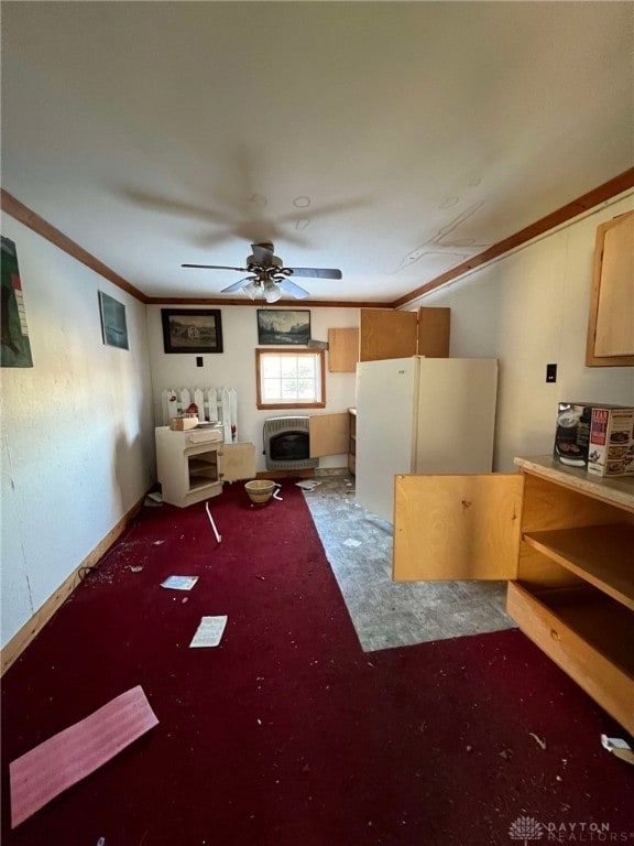 unfurnished living room with ceiling fan, ornamental molding, heating unit, and dark colored carpet