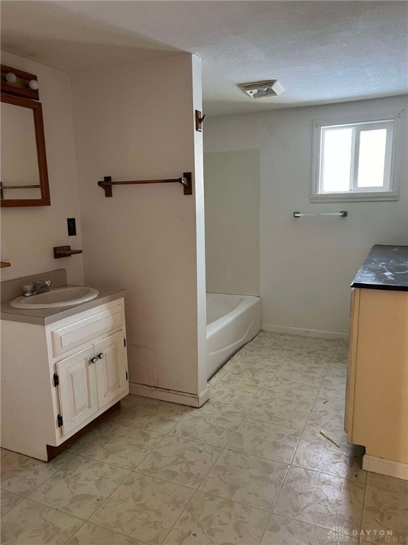 bathroom with vanity, a washtub, and a textured ceiling